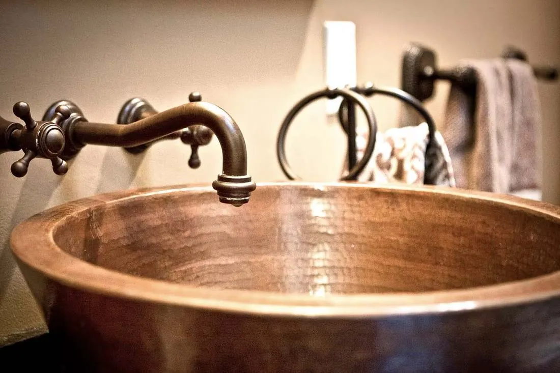 Hammered copper vessel sink with a wall-mounted faucet
