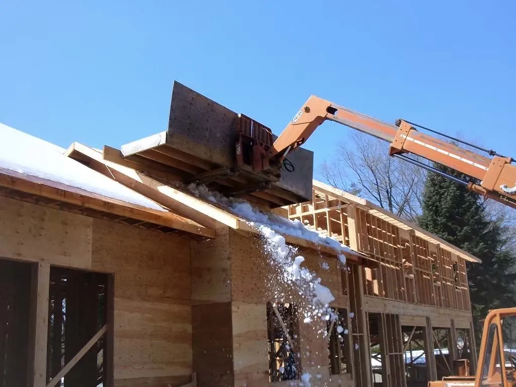Crane clearing snow from framing on a winter job site
